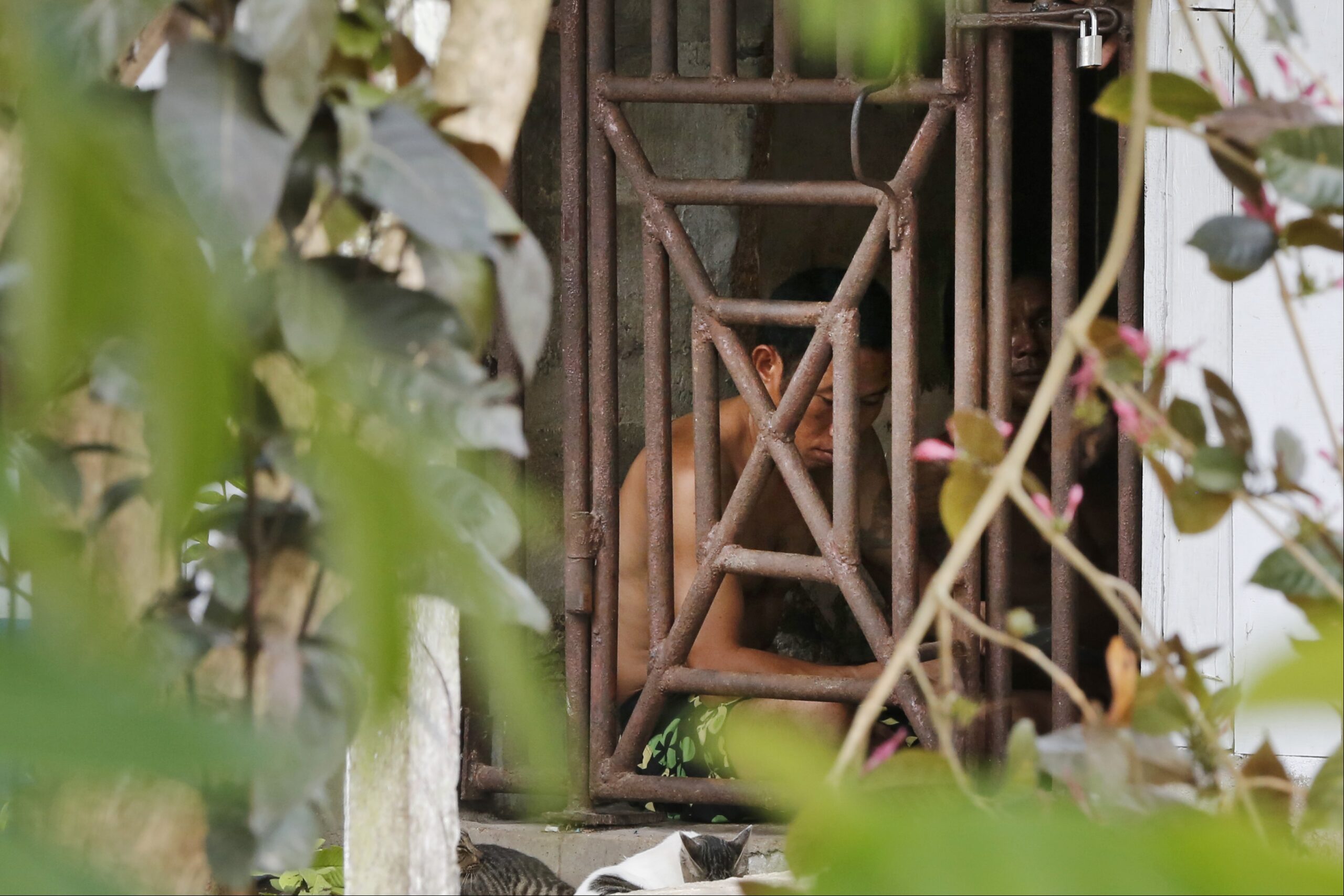 Thai and Burmese fishing boat workers sit behind bars inside a cell at the compound of a fishing company in Benjina, Indonesia. (AP Photo/Dita Alangkara)