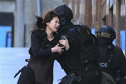 In this Dec. 15, 2014, file photo, Jieun Bae runs to armed tactical response police officers for safety after she escaped from a cafe under siege at Martin Place in the central business district of Sydney, Australia. Rob Griffith, the Sydney-based Associated Press photographer, won the 2015 News Photography award Thursday, Dec. 3, 2015 by the Walkley Foundation for his coverage of the hostage crisis at the Sydney cafe in December 2014. (AP Photo/Rob Griffith, File)