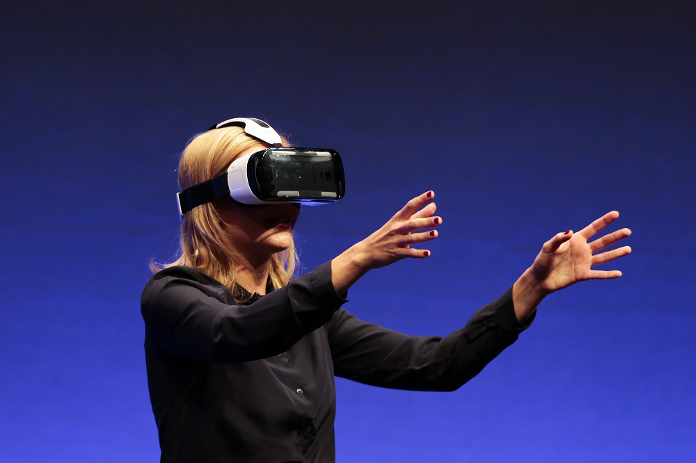 In this Sept. 3, 2014 file photo, British television presenter Rachel Riley shows a virtual-reality headset called Samsung Gear VR of the consumer electronic fair IFA in Berlin. (AP Photo/Markus Schreiber)