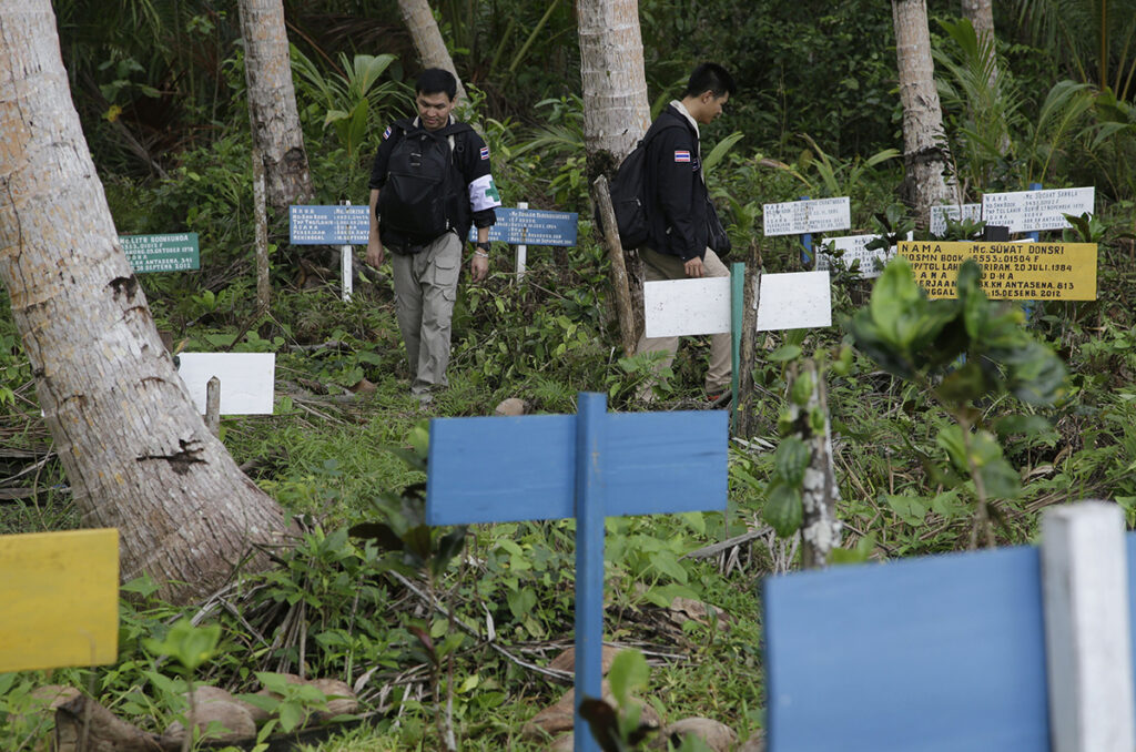 Thai officials inspect the graves of foreign fishermen at a graveyard in Benjina, Aru Islands, Indonesia,
