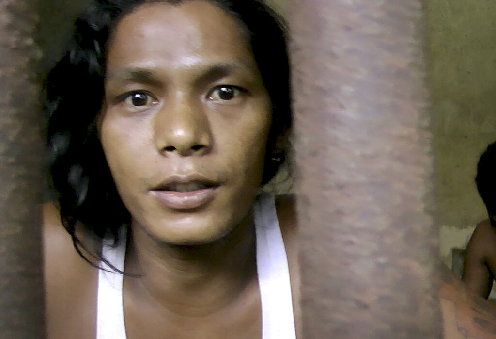 Kyaw Naing, a slave from Myanmar, looks through the bars of a cell at the compound of a fishing company in Benjina, Indonesia, Nov. 27, 2014. Kyaw Naing has since returned home to Myanmar.