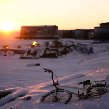 The sun rises over a bicycle covered in snow at the edge of the village in Kaktovik, Alaska, Tuesday, Oct. 15, 2024. (AP Photo/Lindsey Wasson)