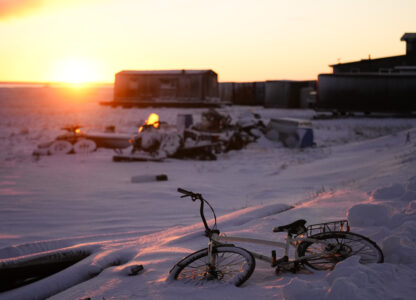 The sun rises over a bicycle covered in snow at the edge of the village in Kaktovik, Alaska, Tuesday, Oct. 15, 2024. (AP Photo/Lindsey Wasson)