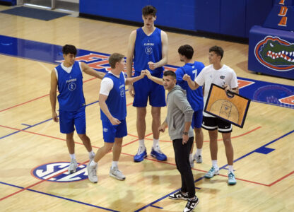 Olivier Rioux, back center, a 7-foot-9 NCAA college basketball player at Florida, gathers with coaches and teammates at the team's practice, Friday, Oct. 18, 2024, in Gainesville, Fla. (AP Photo/John Raoux)