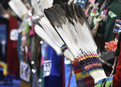 Women hold feather fans during a powwow in Montana on April 6, 2024. (AP Photo/Matthew Brown)