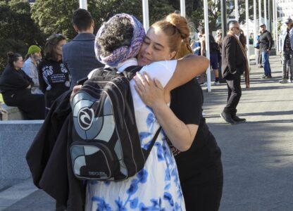 ADDS NAME - Jazmine Te Hiwi, right, embraces a friend as they arrive at Parliament House in Wellington, New Zealand ahead of the apology to the survivors of abuse in state, faith-based and foster care over a period of seven decades, Tuesday, Nov. 12, 2024. (AP Photo/Charlotte Graham-McLay )