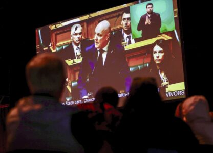 New Zealand's Prime Minister Christopher Luxon is shown on a screen as he makes a 