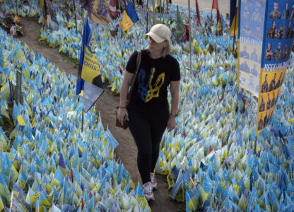 A woman walks through national flags commemorating soldiers who were killed in battles with Russian troops, their names on flags, at the improvised war memorial in Independence Square in Kyiv, Ukraine, Friday, Sept. 27, 2024. (AP Photo/Efrem Lukatsky)