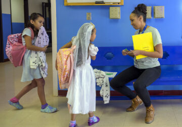 Attendance Clerk Katrice Grant speaks to siblings Melanie Pacheco, 8, left, and Marilynn Pacheco, 5, in the hallway before heading to their classrooms, Tuesday, Oct. 1, 2024, at Algodones Elementary School in Algodones, N.M. (AP Photo/Roberto E. Rosales)