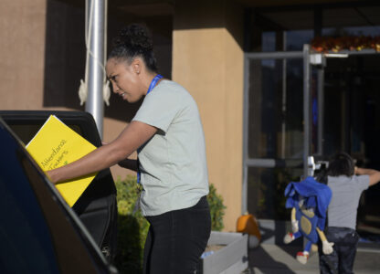 Attendance Clerk Katrice Grant looks to help a student get out a a car as he is dropped off at school, Tuesday, Oct. 1, 2024, at Algodones Elementary School in Algodones, N.M. (AP Photo/Roberto E. Rosales)