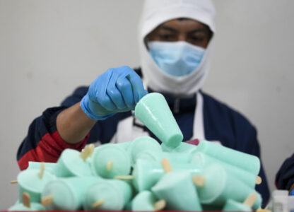 A worker packages popsicles at an artisanal factory in Salcedo, Ecuador, Thursday, Nov. 28, 2024, amid a wave of power outages, triggered by a prolonged dry spell. (AP Photo/Dolores Ochoa)