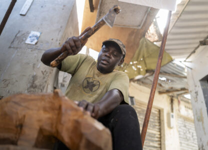Woodcarver Papis Kanté sculpts a wooden hippopotamus to be exhibited in the 