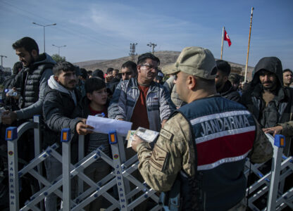 Syrians talk to a Turkish gendarme officer as they wait to cross into Syria from Turkey at the Cilvegozu border gate, near the town of Antakya, southern Turkey, Monday, Dec. 9, 2024. (AP Photo/Metin Yoksu)