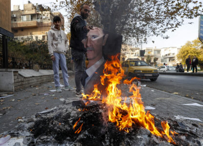 A Syrian man burns a picture of ousted Syrian President Bashar Assad in Damascus, Syria, Monday, Dec. 9, 2024. (AP Photo/Omar Sanadiki)