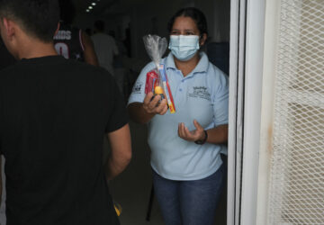 A worker offers personal care kits to Honduran migrants who were deported from the U.S. after they landed at Ramon Villeda Morales Airport in San Pedro Sula, Honduras, Wednesday, Dec. 4, 2024. (AP Photo/Moises Castillo)
