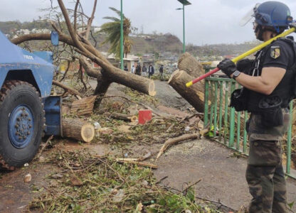 This photo provided on Monday Dec.16, 2024 by the Gendarmerie Nationale, shows a member of the Gendarmerie Nationale watching an armored vehicle clearing a road Sunday, Dec. 15, 2024 in Mayotte as France rushed rescue teams and supplies to its largely poor overseas department in the Indian Ocean that has suffered widespread destruction. (Gendarmerie Nationale via AP)