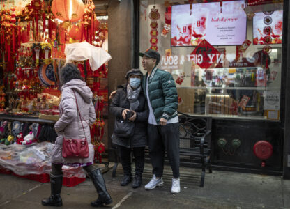 Karho Leung, 33, right, one of the founders of 12 Pell, a local barbershop, serendipitously happens upon his mother as she sits on a bench along Mott Street in Manhattan's Chinatown neighborhood, Thursday, Jan. 25, 2024, in New York. (AP Photo/John Minchillo)