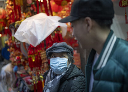 Karho Leung, 33, right, one of the founders of 12 Pell, a local barbershop, serendipitously happens upon his mother as she sits on a bench along Mott Street in Manhattan's Chinatown neighborhood, Thursday, Jan. 25, 2024, in New York. (AP Photo/John Minchillo)