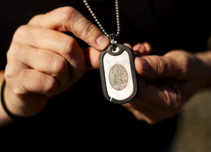 Jen Dold, whose brother, Alex Dold, lived with schizophrenia and died after a 2017 encounter with sheriff's deputies and police officers, holds a dog tag with her brother's fingerprint she wears around her neck Wednesday, Sept. 18, 2024, at a favorite beach of his in Edmonds, Wash. (AP Photo/Lindsey Wasson)