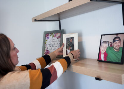 Jen Dold, whose brother, Alex Dold, lived with schizophrenia and died after a 2017 encounter with sheriff's deputies and police officers, adjusts one of her favorite photos of her brother on her living room shelf at her home Wednesday, Sept. 18, 2024, in Edmonds, Wash. (AP Photo/Lindsey Wasson)