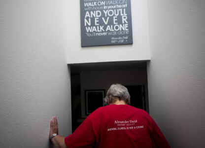 Kathy Duncan, whose son, Alex Dold, lived with schizophrenia and died after a 2017 encounter with sheriff's deputies and police officers, walks down stairs past a piece of art made for her son at the house of her daughter, Jen Dold, Wednesday, Sept. 18, 2024, in Edmonds, Wash. (AP Photo/Lindsey Wasson)