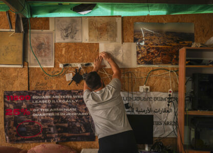 An activist fixes maps of the Armenian quarter on the wall inside a makeshift camp sets up in a parking lot at the Armenian quarter in Jerusalem, Thursday, Nov. 21, 2024. (AP Photo/Francisco Seco)