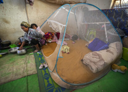 A Kuki tribal woman with a child prepares rice in a relief camp in Kangpokpi, Manipur, Sunday, Dec. 15, 2024. (AP Photo/Anupam Nath)