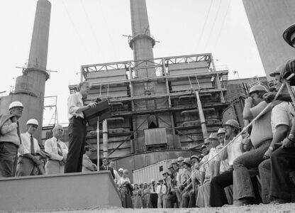 FILE - President Jimmy Carter talks to power plant workers against a backdrop of tall stacks at the Louisville Gas and Electric Company plant in Louisville, Ky., July 31, 1979. (AP Photo, File)