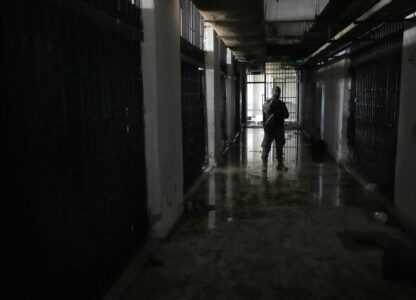 A member of the security forces for the new interim Syrian government stands next to prison cells at the Palestine Branch, a detention facility operated by the General Intelligence Agency during Bashar Assad's regime, in Damascus, Syria, on Dec. 14, 2024. (AP Photo/Hussein Malla)
