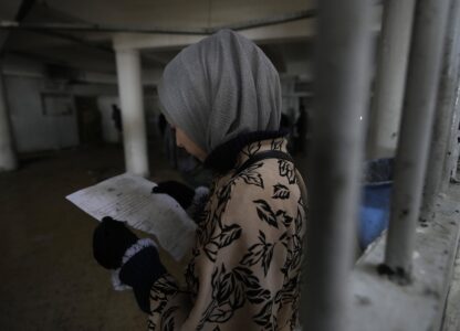 A woman inspects documents in search of the name of a missing relative at Syria's infamous Saydnaya military prison, located just north of Damascus on Dec. 9, 2024. (AP Photo/Hussein Malla)