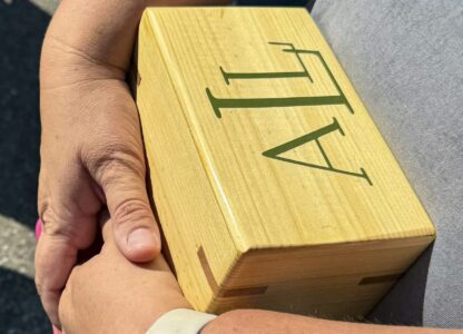 Shannon Doughty holds a wooden box on Aug. 29, 2024, in Westfield, Indiana, that had contained some of the cremated remains of her late brother, Allen Livingston, who was identified in October 2023 as the ninth known victim of suspected serial killer Herbert Baumeister. (AP Photo/Rick Callahan)
