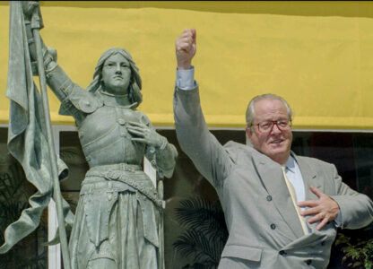 FILE - National Front leader Jean Marie Le Pen mimics Joan of Arc brandishing the French flag before a press conference held Wednesday June 21, 1995 in St Cloud, west of Paris. (AP Photo/Remy de la Mauviniere, File)