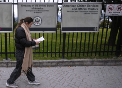 A woman reads a notification about canceling her visa appointment due to Colombian President Gustavo Petro's refusal to accept repatriation flights for Colombian citizens from the United States, outside the U.S. embassy in Bogota, Colombia, Monday, Jan. 27, 2025. (AP Photo/Fernando Vergara)