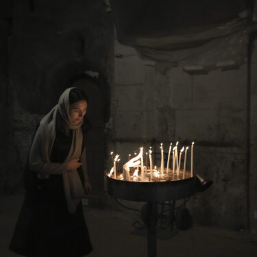 A woman lights candles at the Church of the Holy Sepulchre, where many Christians believe Jesus was crucified, buried and rose from the dead, in the Old City of Jerusalem, Tuesday, Jan. 28, 2025. (AP Photo/Mahmoud Illean)
