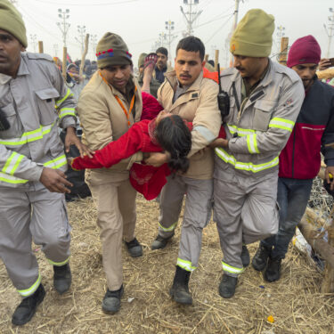 Security officers carry a woman out from the site of a stampede at the Sangam, the confluence of the Ganges, the Yamuna and the mythical Saraswati rivers, on 
