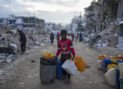 A young Palestinian kid carries jerricans along the destruction caused by the Israeli air and ground offensive in Jabaliya, Gaza Strip, Wednesday, Feb. 5, 2025. (AP Photo/Abdel Kareem Hana)