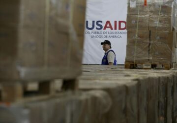 FILE - A man walks past boxes of USAID humanitarian aid at a warehouse at the Tienditas International Bridge on the outskirts of Cucuta, Colombia, Feb. 21, 2019, on the border with Venezuela. (AP Photo/Fernando Vergara, File)