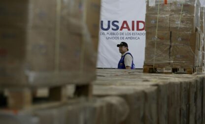 FILE - A man walks past boxes of USAID humanitarian aid at a warehouse at the Tienditas International Bridge on the outskirts of Cucuta, Colombia, Feb. 21, 2019, on the border with Venezuela. (AP Photo/Fernando Vergara, File)