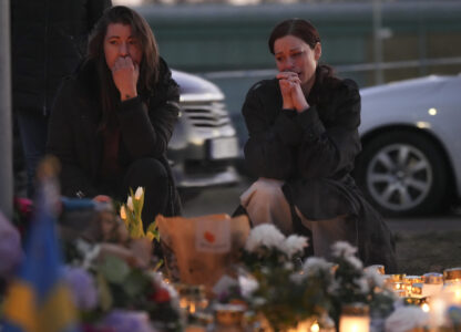 Two women stand by candles and flowers during a vigil near the scene of a shooting at an adult education center on the outskirts of Orebro, Sweden, Thursday, Feb. 6, 2025. (AP Photo/Sergei Grits)