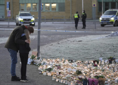 People comfort each other at a makeshift memorial, near the scene of a shooting, on the outskirts of Orebro, Sweden, Friday, Feb. 7, 2025. (AP Photo/Sergei Grits)