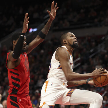 Phoenix Suns forward Kevin Durant, right, drives to the basket past Portland Trail Blazers center Deandre Ayton during overtime of an NBA basketball game Monday, Feb. 3, 2025, in Portland, Ore. (AP Photo/Amanda Loman)