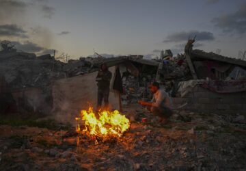 FILE - Palestinians sit by a fire next to their tent in an area littered with rubble from buildings demolished during the Israeli army's ground and air offensive against Hamas in Gaza City, Tuesday Feb.4, 2025. (AP Photo/Abdel Kareem Hana, file)