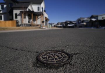 A cover with the word water is visible on a street that is used to access a water main line Thursday, Feb. 13, 2025, in Louisville, Colo.(AP Photo/Brittany Peterson)