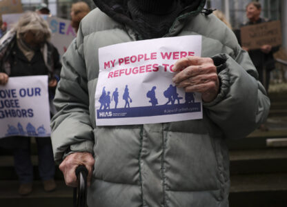 Martin Bernstein, 95, whose parents were refugees, holds a sign as people gather outside the U.S. District Court after a federal judge blocked President Donald Trump's effort to halt the nation's refugee admissions system Tuesday, Feb. 25, 2025, in Seattle. (AP Photo/Ryan Sun)