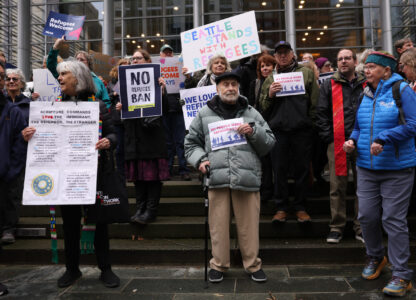 Martin Bernstein, 95, whose parents were refugees, at center, holds a sign as people gather outside the U.S. District Court after a federal judge blocked President Donald Trump's effort to halt the nation's refugee admissions system Tuesday, Feb. 25, 2025, in Seattle. (AP Photo/Ryan Sun)