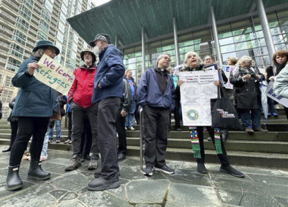 People gather outside the U.S. District Court after a federal judge blocked President Donald Trump's effort to halt the nation's refugee admissions system Tuesday, Feb. 25, 2025, in Seattle. (AP Photo/Eugene Johnson)