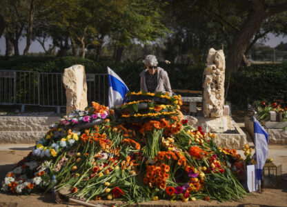 A woman pays tribute at the joint grave of slain hostages Shiri Bibas and her two children, Ariel and Kfir, following their funeral in Tzohar, southern Israel, Wednesday, Feb. 26, 2025. The mother and her two children were abducted by Hamas on Oct. 7, 2023, and their remains were returned from Gaza to Israel last week as part of a ceasefire agreement with Hamas. (AP Photo/Ohad Zwigenberg)