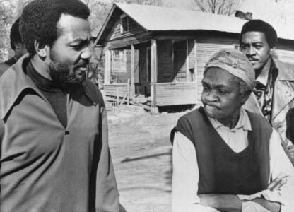FILE - Former football great Jim Brown, left, president of the Black Economic Union, talks with Anne Faulkner, 74, in her Holly Springs, Miss., neighborhood, on Feb. 11, 1970. Brown led about 25 Black athletes for the firsthand look at conditions his BEU hopes to improve. At right is Leroy Kelly of the Cleveland Browns. (AP Photo/File)