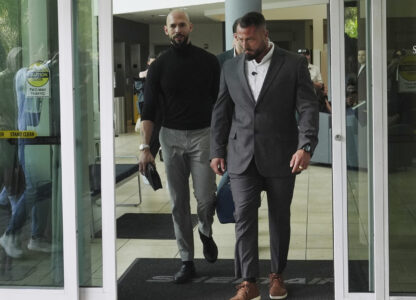 Influencer Andrew Tate, left, arrives, Thursday, Feb. 27, 2025, in Fort Lauderdale, Fla. Andrew and his brother Tristan were charged with human trafficking in Romania and arrived in the U.S. after authorities lifted travel restrictions. (AP Photo/Marta Lavandier)