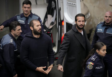 FILE- Police officers escort Andrew Tate, center, handcuffed to his brother Tristan Tate, to the Court of Appeal in Bucharest, Romania, Monday, Feb. 27, 2023. (AP Photo/Andreea Alexandru, File)